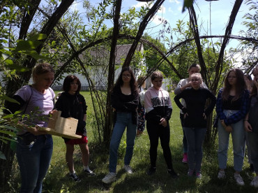 Visitors under the willow labyrinth listen to a speaker about birdhouses.