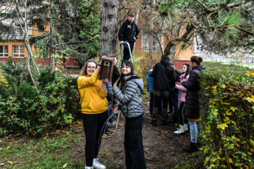 Študentky držia vtáčiu búdku pred stromom, na ktoré sa umiestní búdka.